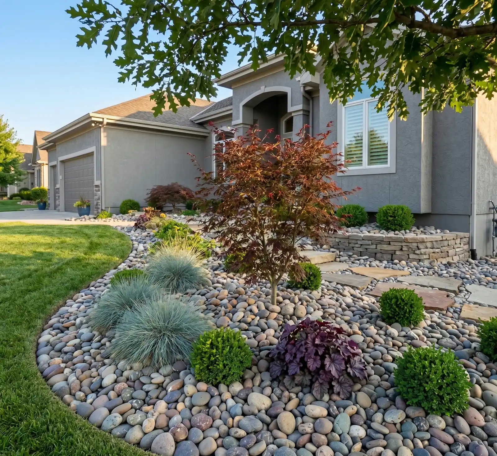 Example river rock landscape bed with ornamental plants beside a home