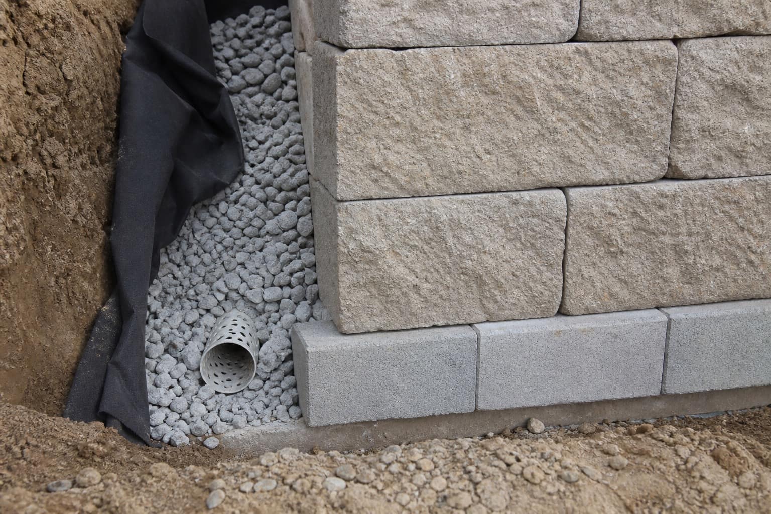Close-up of retaining wall base with gravel drainage at the footer