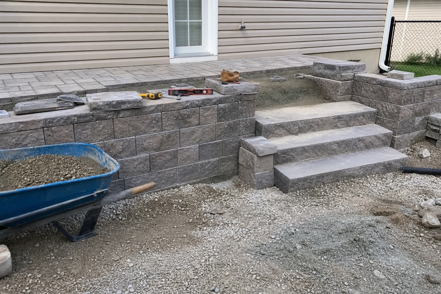 Low paver sitting wall and step detail beside a patio under construction