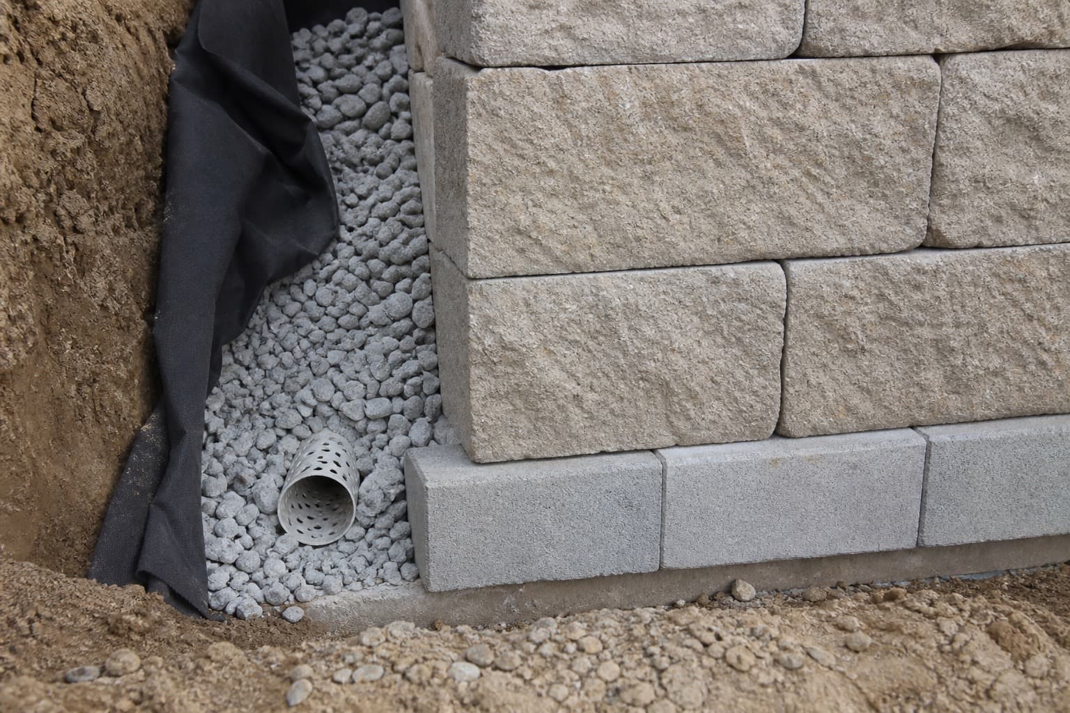 Close-up of retaining wall base with gravel drainage at the footer
