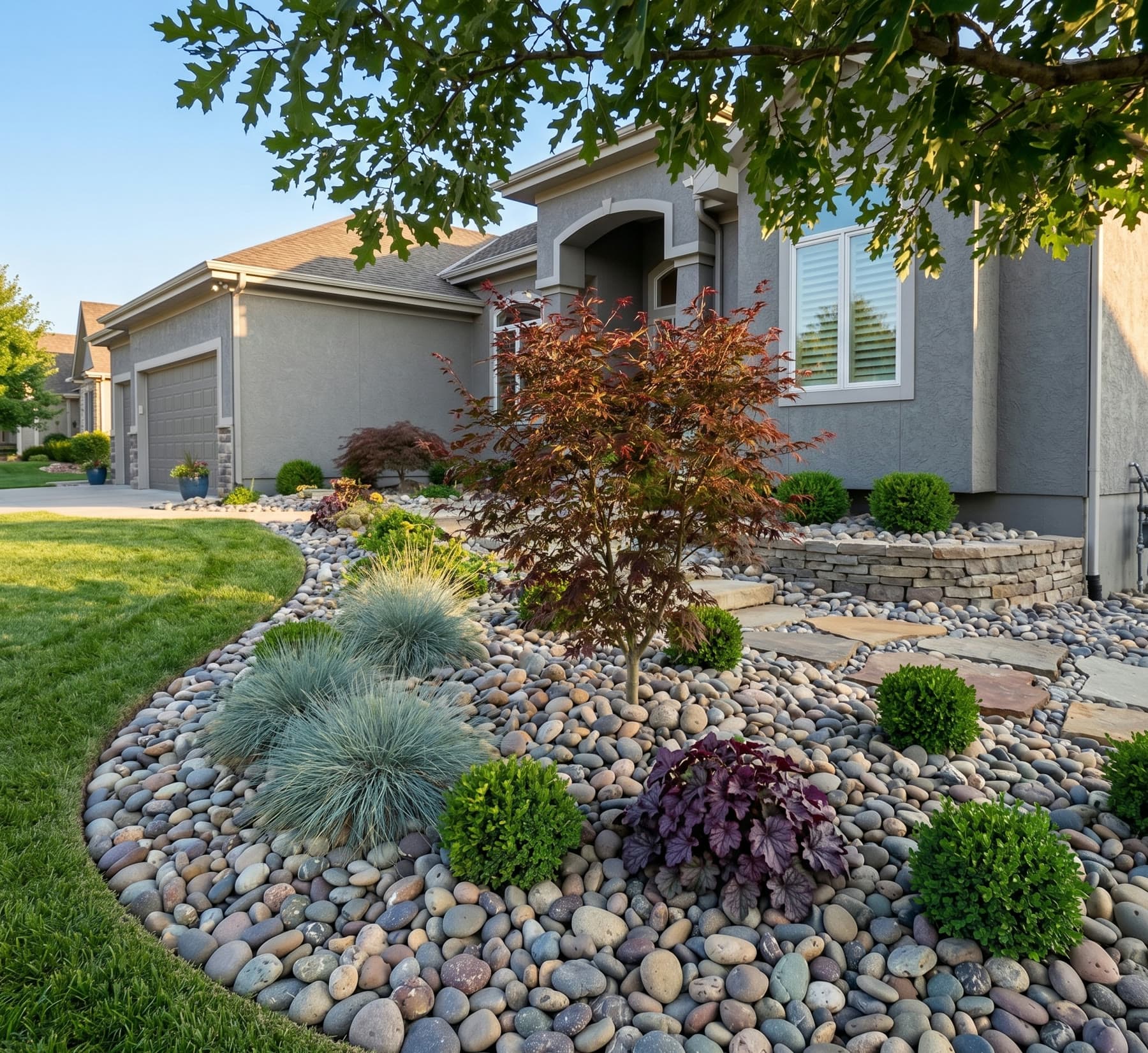 Example river rock landscape bed with ornamental plants beside a home